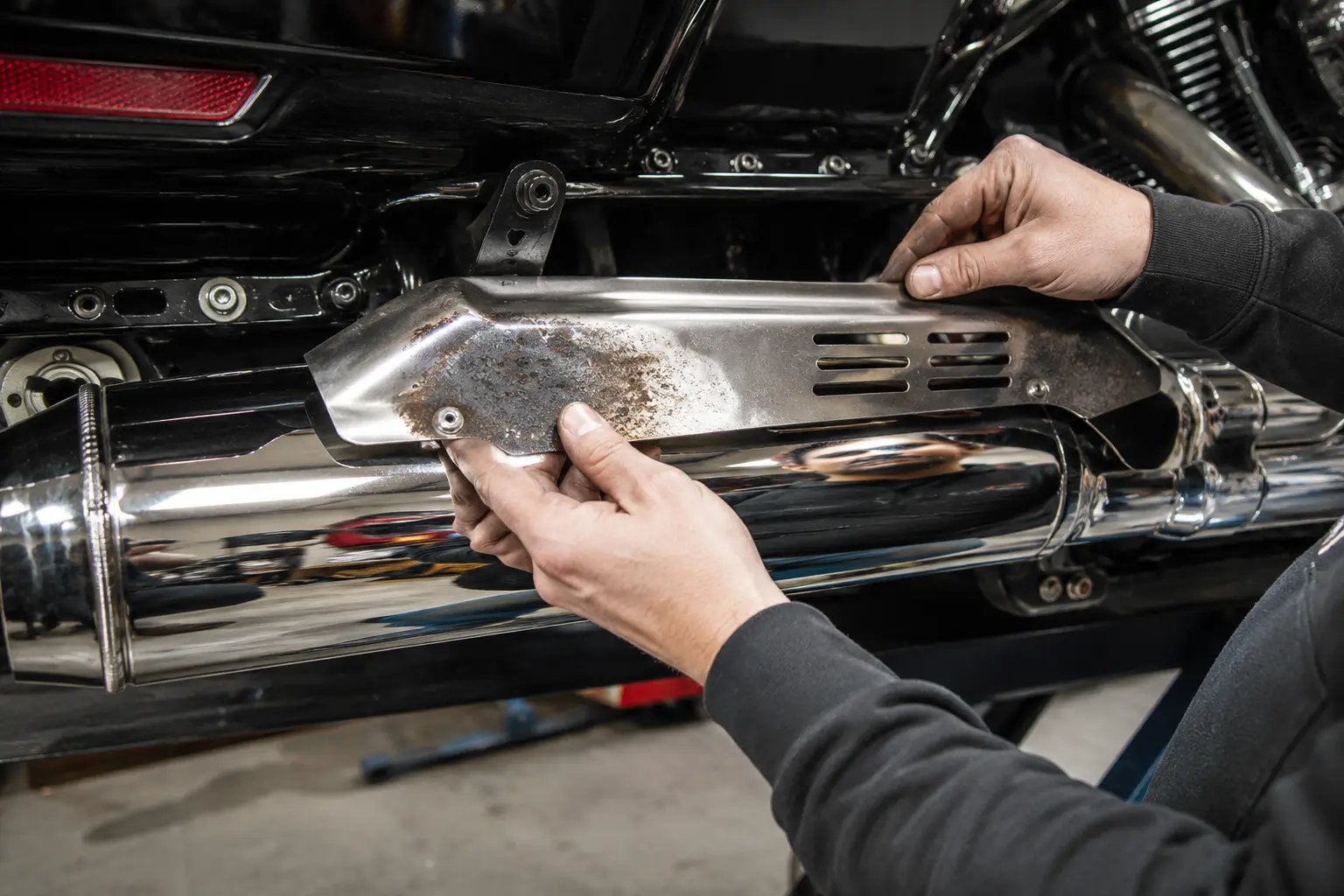 Mechanic replacing a worn Harley Road Glide exhaust heat shield
