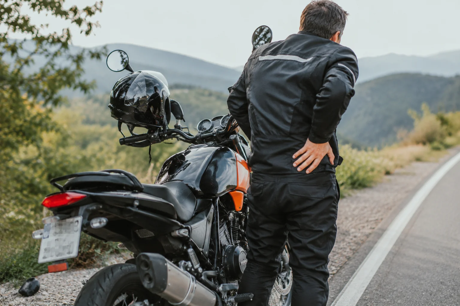Motorcyclist experiencing seat discomfort after a long ride beside his bike