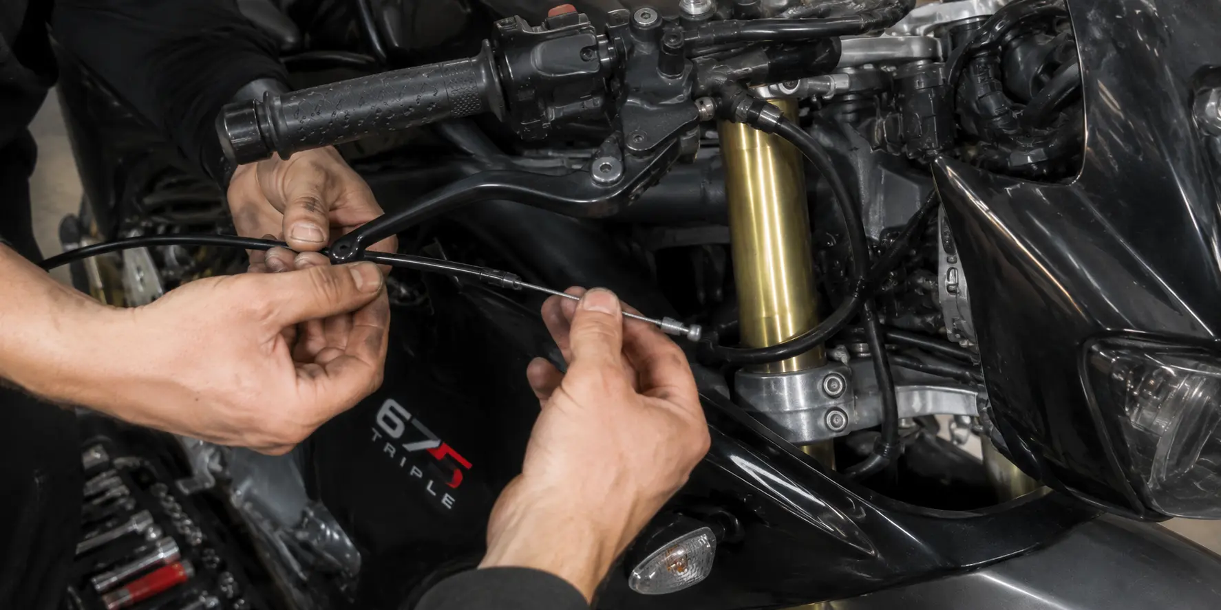 Mechanic replacing the brake cable on a Triumph 675 Triple motorcycle